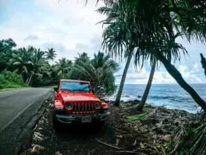 A red Jeep pulled over on the side of a coastal road on the Bi Island